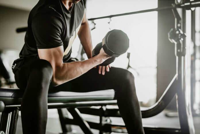 man-doing-concentration-curls-exercise-working-out-with-dumbbell